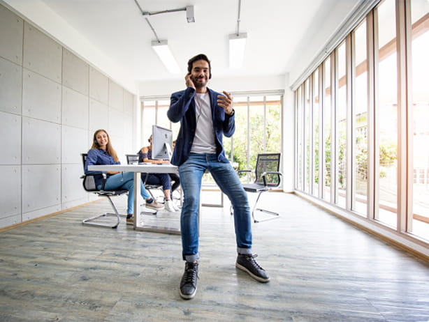 Office worker sitting on desk taking a phgone call